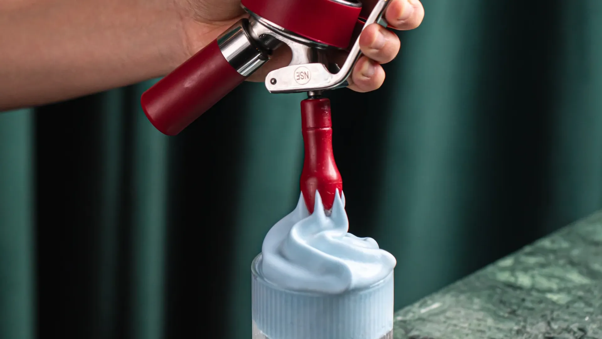 Stainless steel whipped cream dispensers lined up for comparison testing in a commercial kitchen | Champion Whip