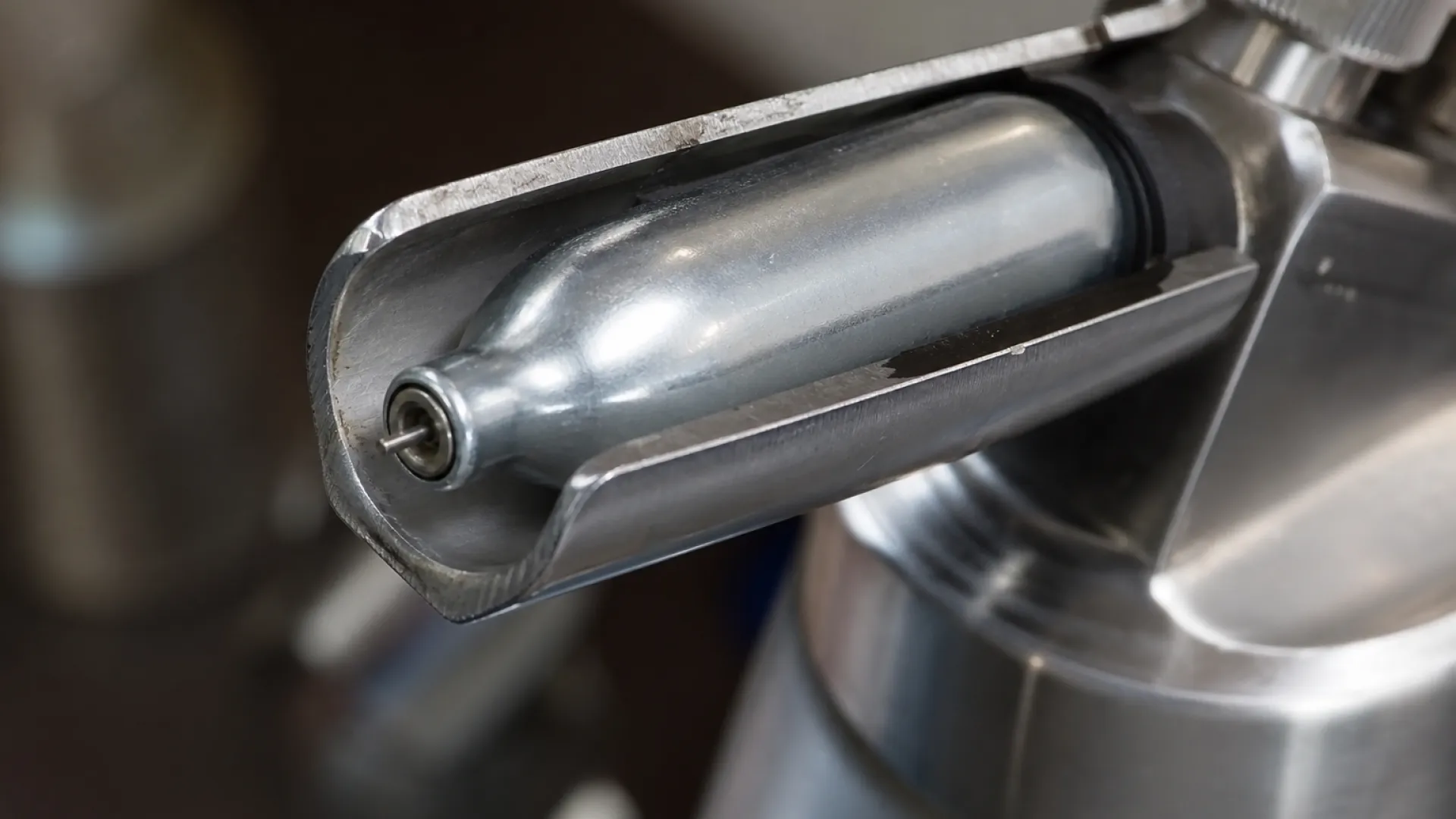 Cutaway view of a cream charger being pierced inside the charger holder of a dispenser